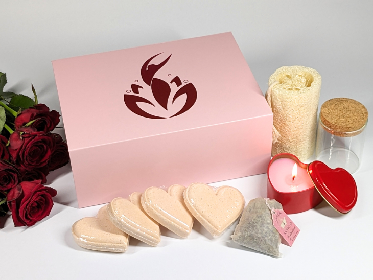 The BathCalm Romance Gift Box features the Ambrosian Romance blend of Buddha Wood, Honeysuckle and Cardamom pure essential oils. Each BathCalm Romance Gift Box includes: 4 x Ambrosian Romance Love Bombs 1 x BathCha bag with epsom salts and rose petal botanicals 1 x Glass jar with cork lid 1 x pink Sandalwood fragrance candle in red love heart tin 1 x 5 inch loofah, all nestled in a lovely pretty pink magnetic closure box with metallic pink BathCalm Logo on top.